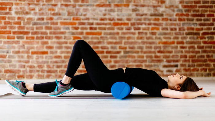 Woman recovering from beginner powerlifting program with foam roller