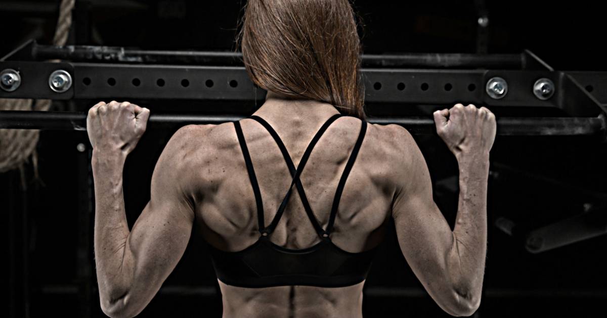 female performing pull up showing highly developed back muscles from ultimate program