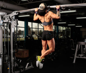 negative pull up demonstrated by muscular and sculpted female athlete