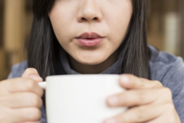 woman drinking out of a coffee cup
