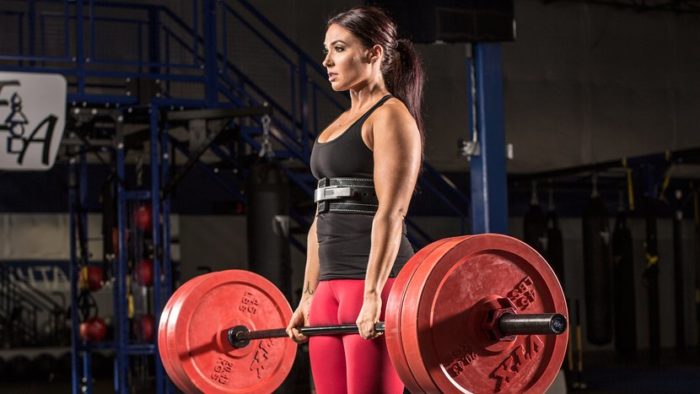 Woman a the top of a deadlift in powerlifting vs bodybuilding