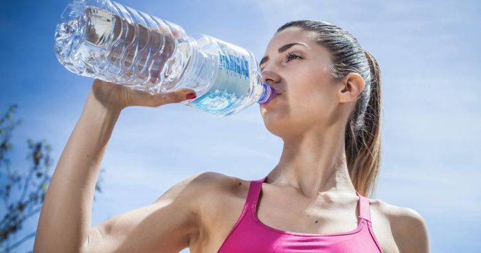 Woman drinking water to avoid dehydration after a pre-workout