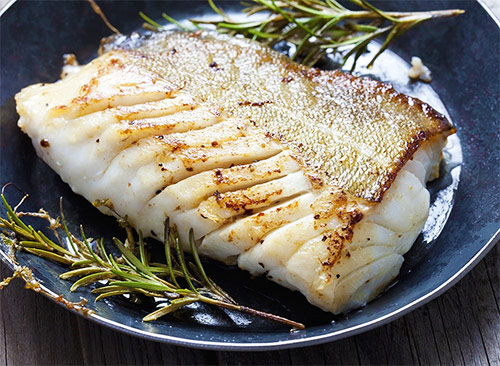 a fillet of cod cooked with herbs on a plate as a high protein source