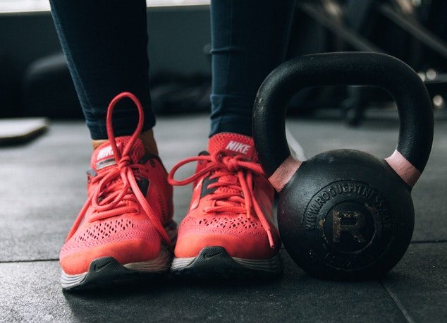 woman standing next to kettlebell ahead of a HIIT workout plan