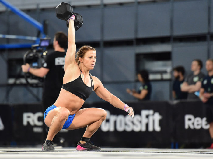 Woman competing in a crossfit competition at the bottom of a dumbbell snatch